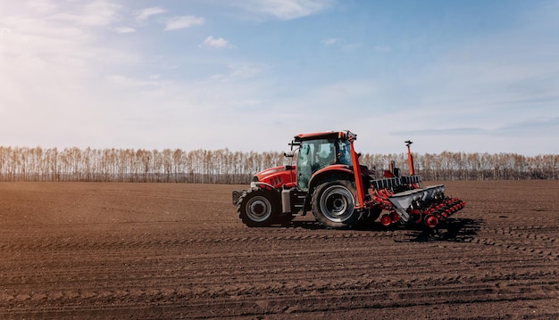 Temporada de semeadura da primavera Agricultor com um trator semeia sementes de milho em seu campo Plantando milho com plantador rebocado Semeadura agrícola O conceito de agricultura e máquinas agrícolas