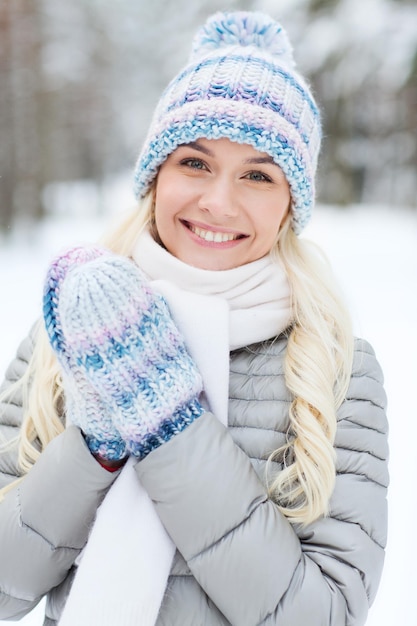 temporada, navidad y concepto de la gente - mujer joven sonriente feliz en el bosque de invierno