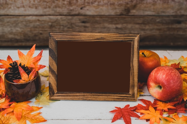 Temporada de otoño y otoño. Marco de fotos vacío y hoja de arce falsa en la mesa de madera. Cosecha cuerno de la abundancia y concepto del día de acción de gracias.