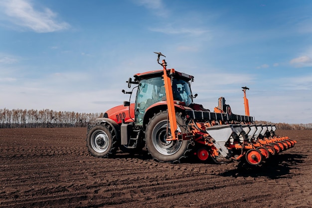 Temporada de siembra de primavera Agricultor con un tractor siembra semillas de maíz en su campo Siembra de maíz con sembradora remolcada Siembra agrícola El concepto de agricultura y maquinaria agrícola