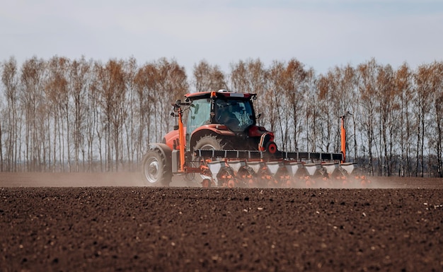 Temporada de siembra de primavera Agricultor con un tractor siembra semillas de maíz en su campo Siembra de maíz con sembradora remolcada Siembra agrícola El concepto de agricultura y maquinaria agrícola