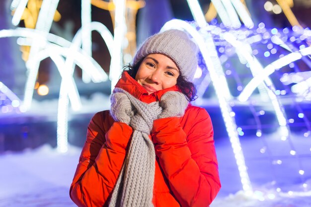 Temporada de vacaciones de invierno. Navidad, concepto de año nuevo. Mujer feliz divertida pasar tiempo divirtiéndose cerca de escaparate iluminado y decorado en la calle de la ciudad.