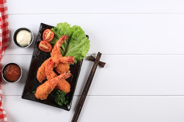 Tempura de camarones o gambas, cocina tradicional japonesa hecha de camarones fritos cubiertos con pan rallado o panko, generalmente se encuentra como menú de almuerzo Bento. Sobre fondo de madera blanca con espacio de copia