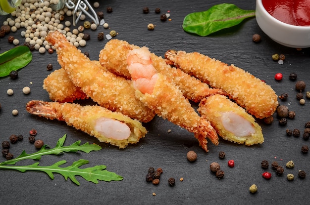 Tempura de camarão frito com molho de pimenta doce em uma placa de pedra preta