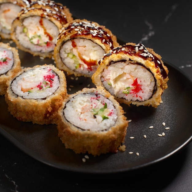 Tempura Ebi Heiß gebratene Sushi-Rollen und Maki mit Garnelen auf schwarzem Stein