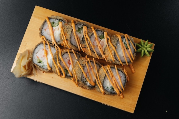 Tempura sushi maki con camarones y salsa sobre tabla de madera