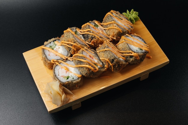 Tempura sushi maki con camarones y salsa sobre tabla de madera