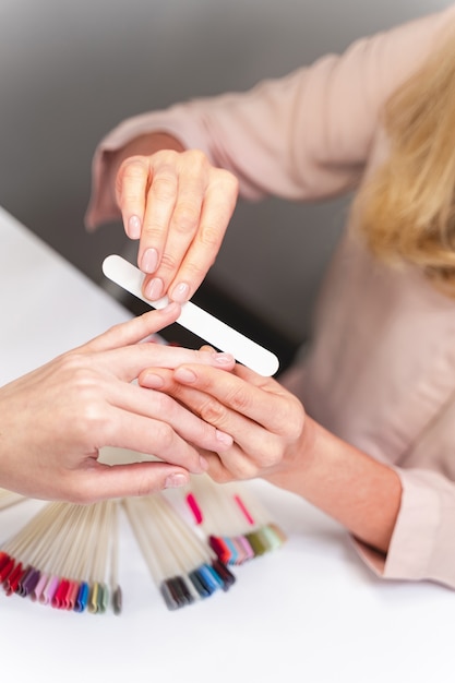 Ten cuidado. Foto enfocada en la mano femenina que usa lima de uñas durante el procedimiento de belleza. Concepto de belleza