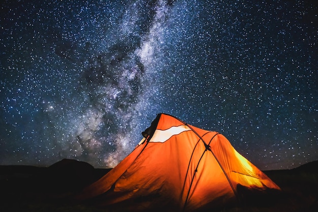 Tenda en el campo contra el cielo estrellado por la noche
