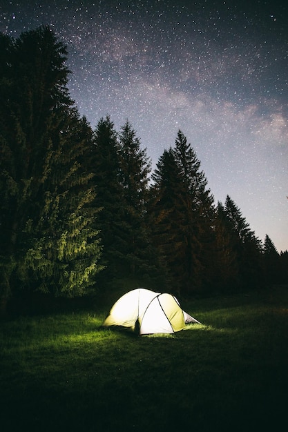 Tenda en el campo contra el cielo por la noche