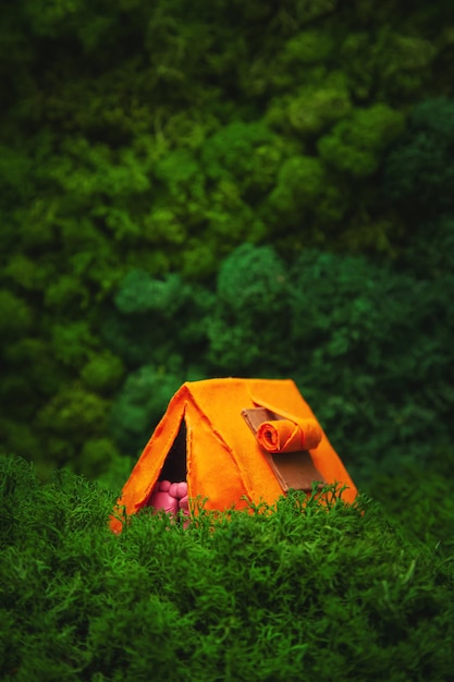 Tenda laranja em miniatura sobre um fundo natural O conceito de viagens ecológicas e turismo