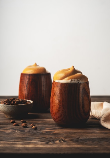 Foto tendencia bebida coreana, café batido esponjoso, café dalgona, vasos de madera vintage con una bebida