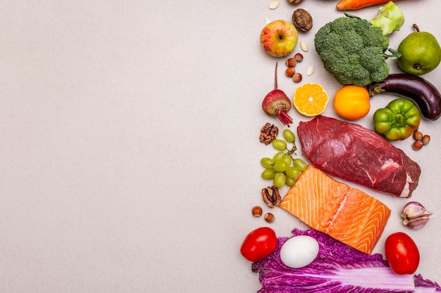 Foto tendência da dieta paleo / pegan. conceito de comida equilibrada saudável. conjunto de produtos frescos, carne crua, salmão, legumes e frutas