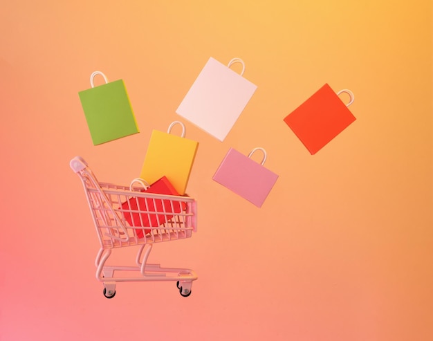 Tendência da sociedade de consumo Carrinho de compras e sacos coloridos