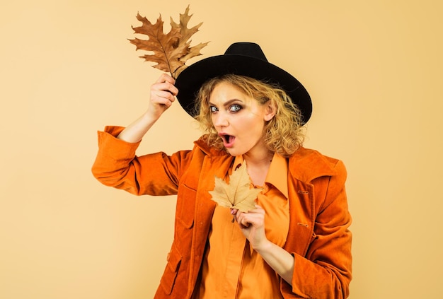 Foto tendencia de la moda para el otoño hermosa chica sorprendida en naranja elegante abrigo de camisa y sombrero negro otoño