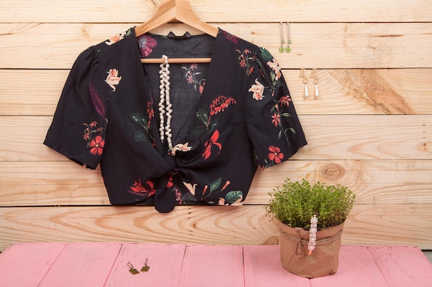 Tendências da moda Blusa crop top preta com estampa floral em cabide e brincos de pérolas de cabelo jóias