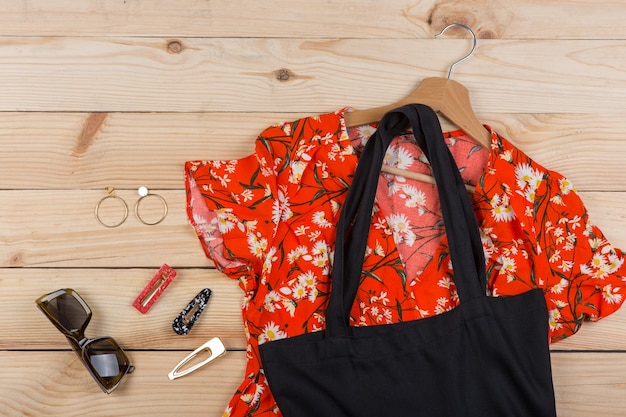 Tendências da moda óculos de sol preto eco tote bag vestido com estampa floral em cabide e brincos de joias