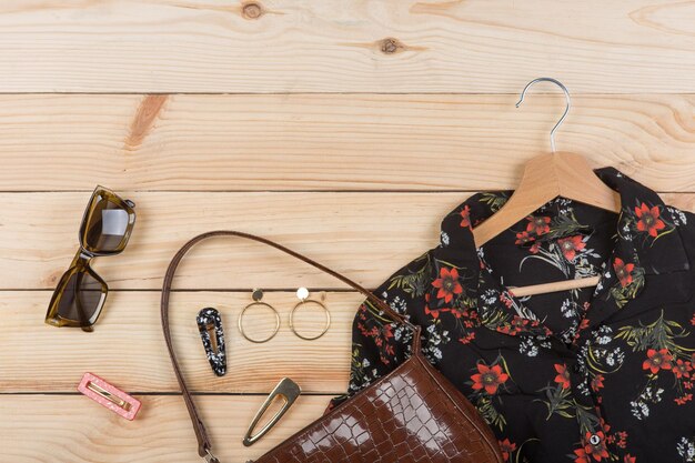 Tendencias de moda, gafas de sol, blusa de bolso marrón con estampado floral en percha y pendientes de pasador de joyería