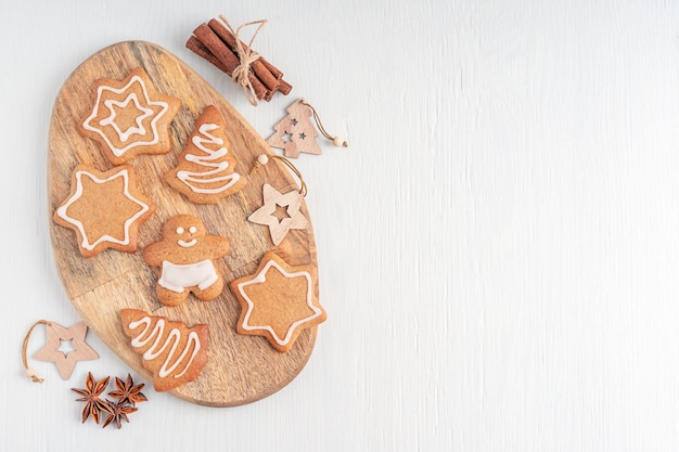 Foto tendido plano con galletas de jengibre dulces caseras en una tabla de cortar sobre fondo blanco de madera