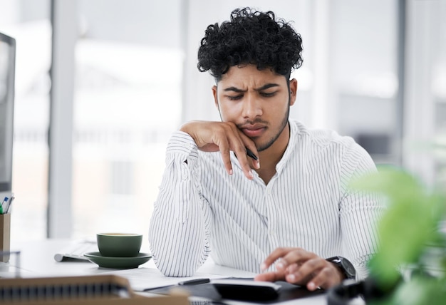 Tendo alguns problemas com questões de dinheiro Foto de um jovem empresário parecendo estressado enquanto usa uma calculadora em um escritório