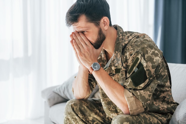 Tendo flashbacks Transtorno de estresse pós-traumático Soldado de uniforme sentado dentro de casa