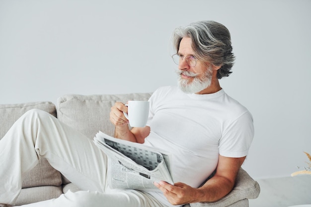 Tendo tempo livre Homem moderno elegante sênior com cabelos grisalhos e barba dentro de casa