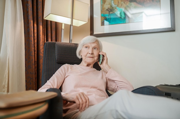 Tendo uma chamada. Senhora elegante de cabelos curtos, falando ao telefone