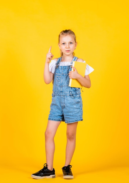 Tendo uma nova ideia garota leu o livro de volta à escola e conceito de infância aluno em fundo amarelo garoto com aparência inteligente e roupa casual conceito de educação moderna inspirado com ideia