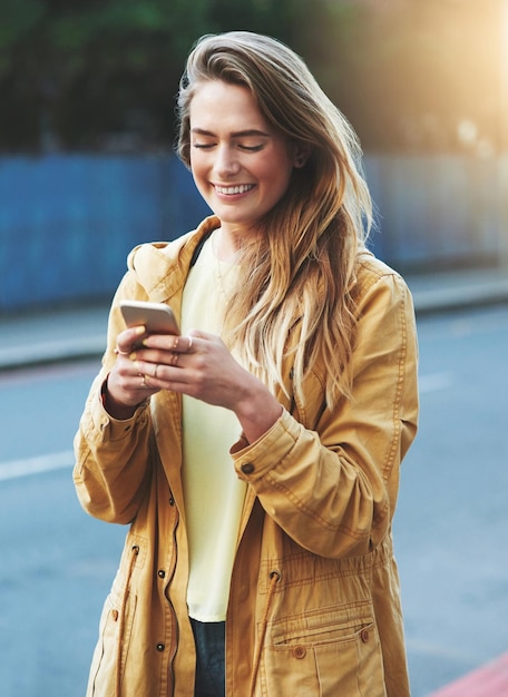 Tendré a mis amigos aquí en un abrir y cerrar de ojos Fotografía de una mujer joven que usa su teléfono celular mientras está en la ciudad