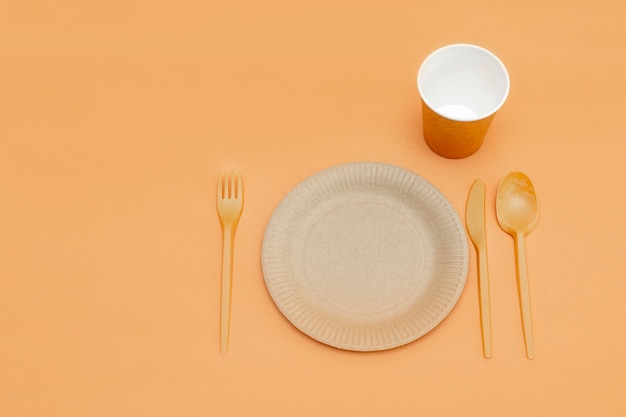 Tenedor, cuchara, cuchillo, plato y taza reciclables sobre un fondo beige. Utensilios de cocina. Vista superior. Estilo minimalista. Copia espacio