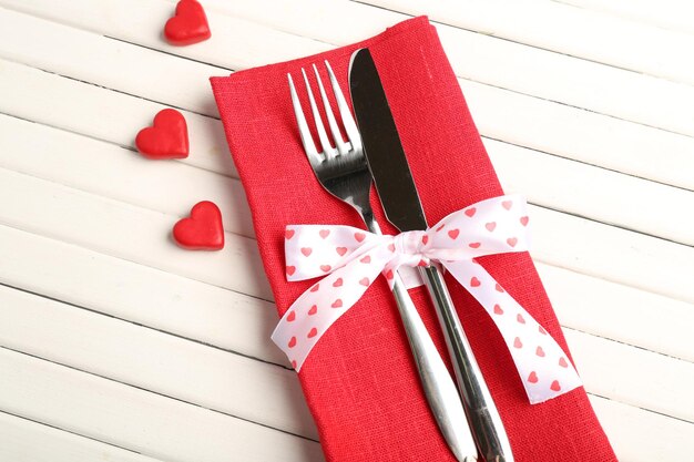 Tenedor y cuchillo con corazones decorativos sobre mesa de madera