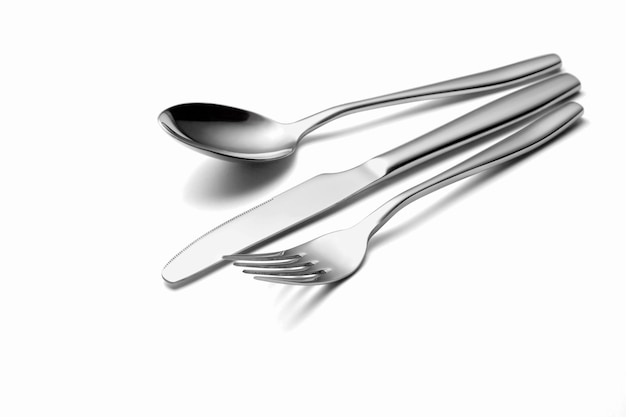 El tenedor y el cuchillo de cuchara de metal brillante en un blanco