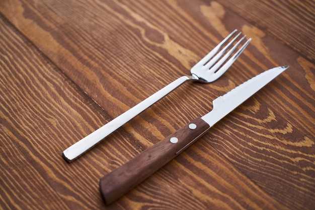 Tenedor y cuchillo en la mesa de madera