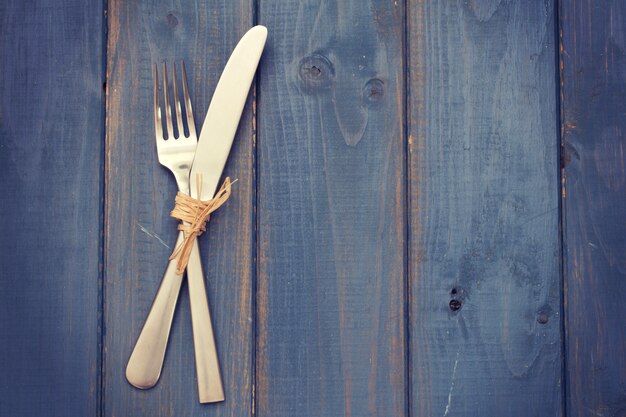 Tenedor y cuchillo sobre superficie de madera azul