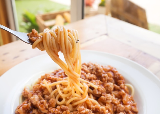 Tenedor enrollar los espaguetis. Espagueti con salsa de tomate de cerdo. Sabor dulce.