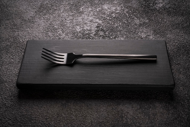 Un tenedor de mesa negro en un podio de madera. Bodegón minimalista con estilo.