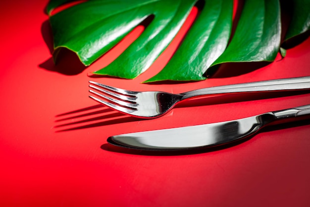 Tenedores de plata y laeves verdes sobre fondo rojo Flatlay Mockup