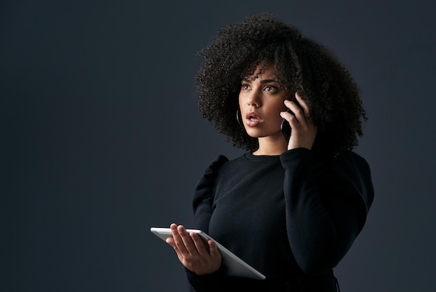 Tenemos un gran problema Toma de una joven empresaria usando su teléfono inteligente y tableta digital contra un fondo de estudio