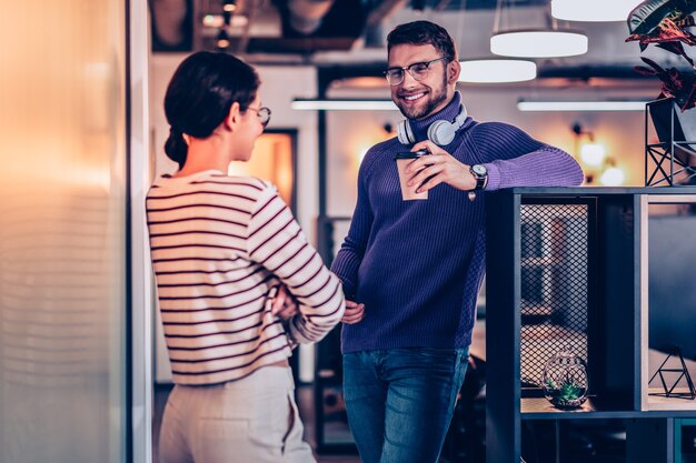 Tener descanso. Hombre guapo con barba manteniendo una sonrisa en su rostro mientras habla con su pareja