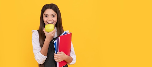 Tener hambre de nuevos conocimientos Escolar feliz comer manzana Retrato de colegiala estudiante estudio banner encabezado Escuela niño cara copyspace