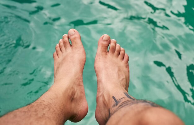 Tener una idea del agua Toma de ángulo alto de los pies de un hombre sobre el agua