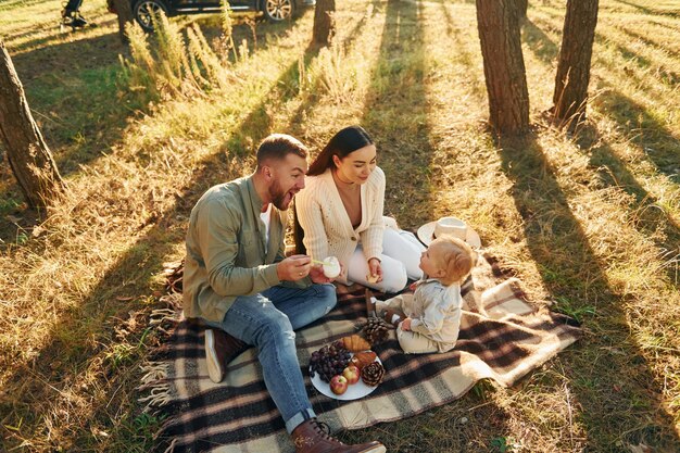 Tener picnik Familia feliz de padre madre e hija pequeña está en el bosque