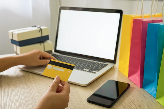 Tener una tarjeta de crédito en la mano mientras usa una computadora portátil en la mesa