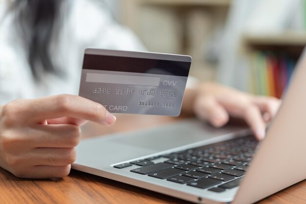 Foto tener una tarjeta de crédito en la mano y usar la computadora en línea para comprar o pagar facturas