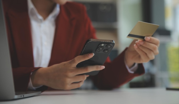Tener la tarjeta de crédito en la mano y usar una computadora portátil Mujer de negocios o empresaria que trabaja desde casa Compras en línea comercio electrónico banca por Internet gastar dinero Trabajo desde casa concepto
