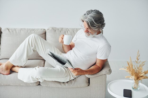 Tener tiempo libre Senior hombre moderno con estilo con pelo gris y barba en el interior