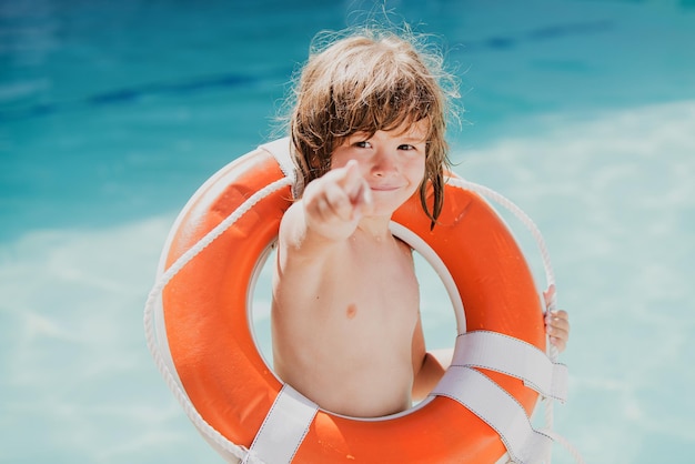 Tenga cuidado con los niños del agua que salvan la vida ayudando al niño del concepto con el círculo de rescate en la playa de verano