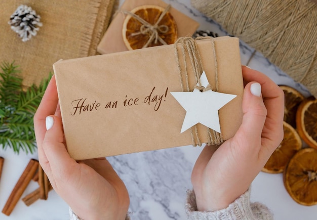 Tenga un día de hielo Inspiración broma cita frase Mujer haciendo Caja con regalos de Año Nuevo envueltos en papel artesanal y decorado con rama de abeto Concepto de vacaciones y regalos Hecho a mano Ecológico