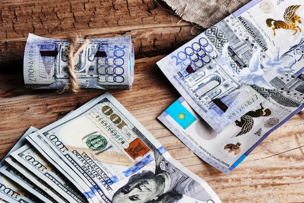 Tenge e dólares. Cazaquistão e dinheiro de papel americano em um fundo de madeira.