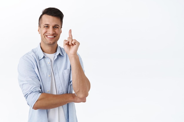 Tengo una idea Retrato de un hombre apuesto, inteligente y feliz levantando un dedo y sonriendo proponer una buena sugerencia tener un plan perfecto o una solución pensar qué hacer de pie fondo blanco